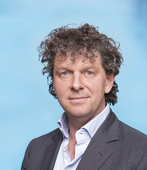 a man with curly hair looks into the camera