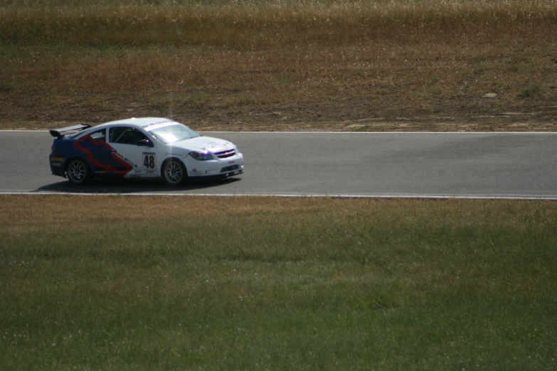 a white sports car driving around a race track