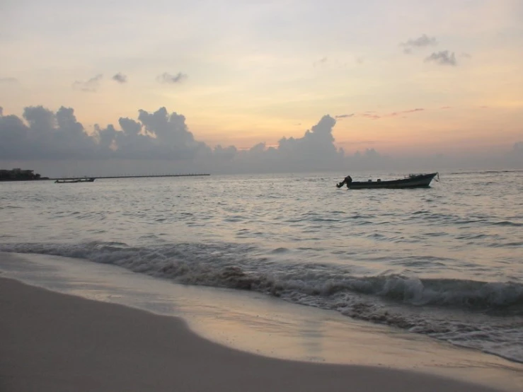 there is a small boat sitting on the water in the ocean