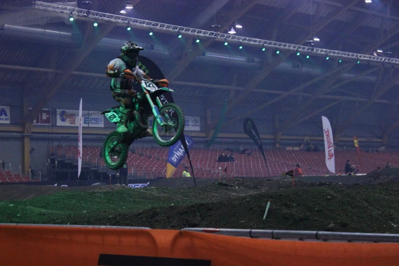 a person in black and green rides on a dirt bike