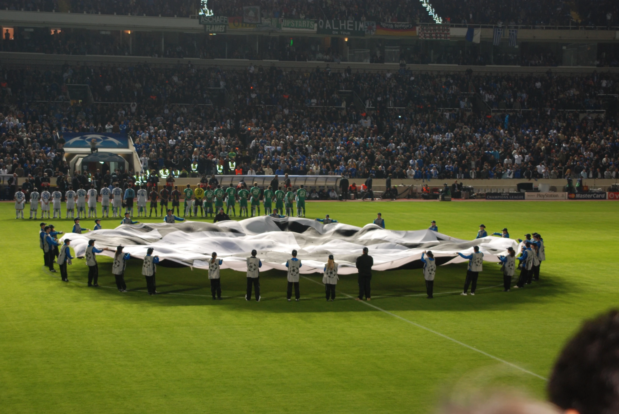 a group of people stand around a giant umbrella