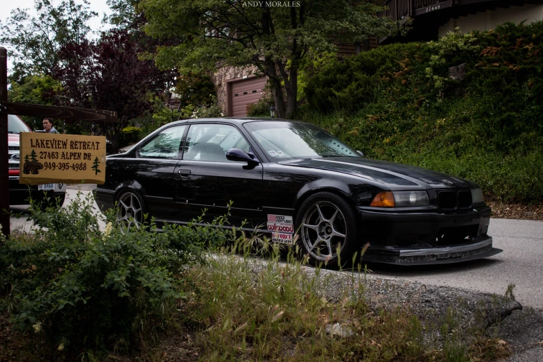 black car with sign on the front parked in the gravel