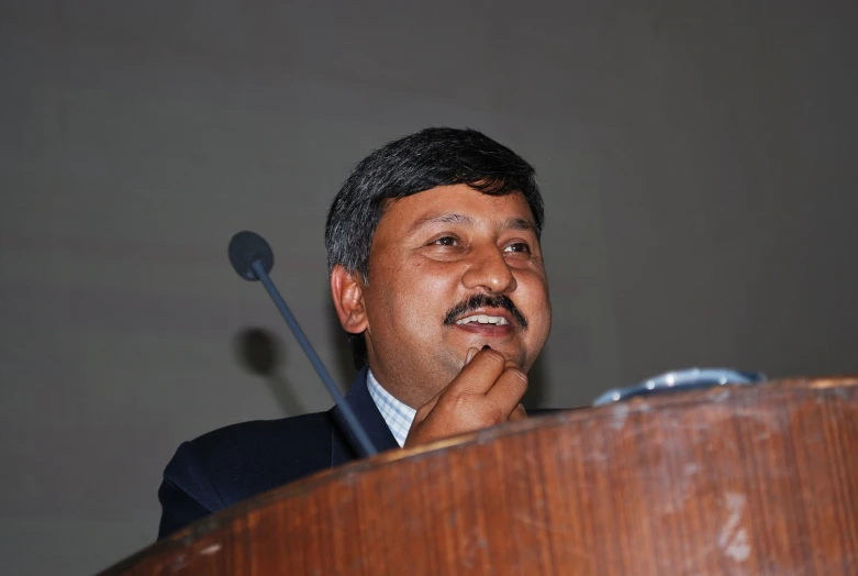 a man speaking from a podium with microphone in front of him