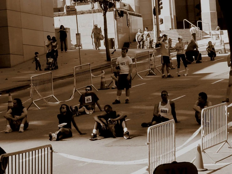 people sitting in front of buildings with gates and a crowd watching