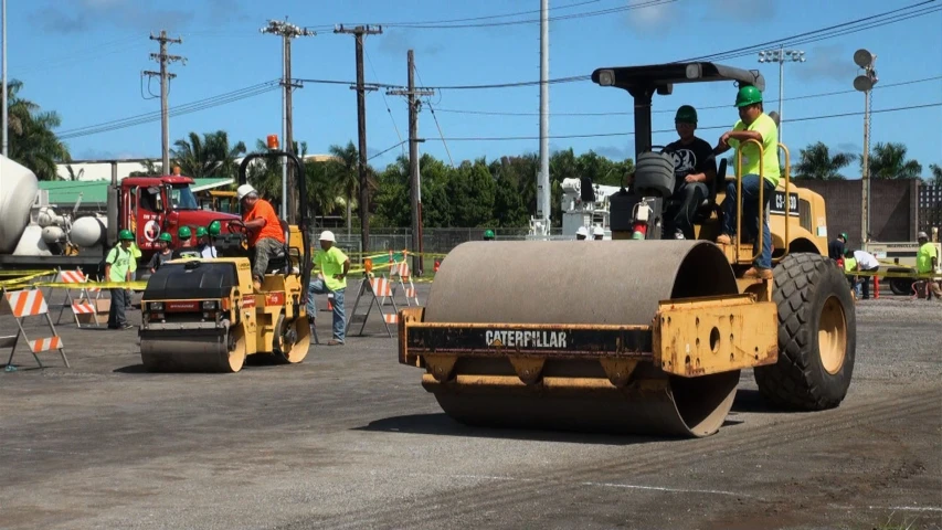 two workers are driving a large, yellow bulldozer