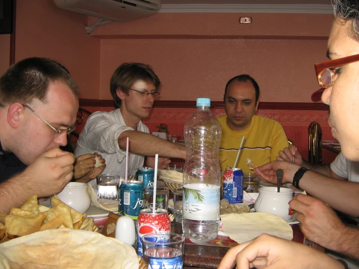 group of men at table eating with drinks and food