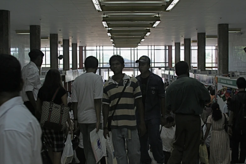 three men standing in an airport terminal with lots of people
