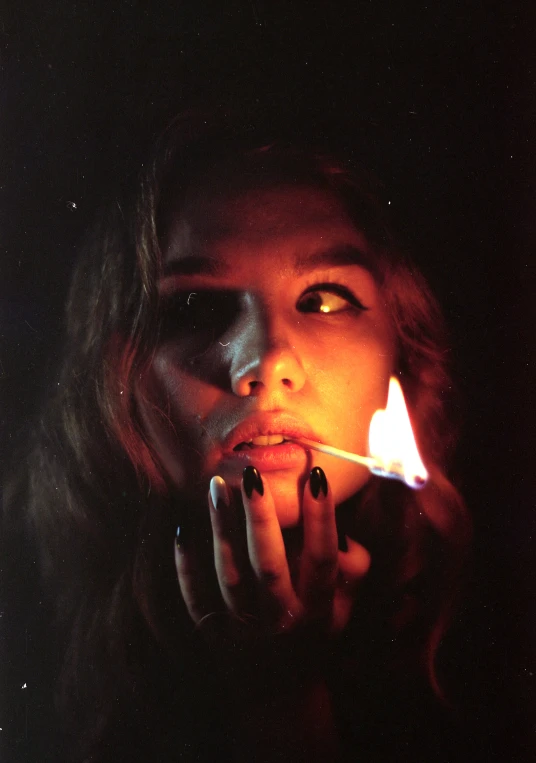 a woman is smoking while holding her finger in the dark