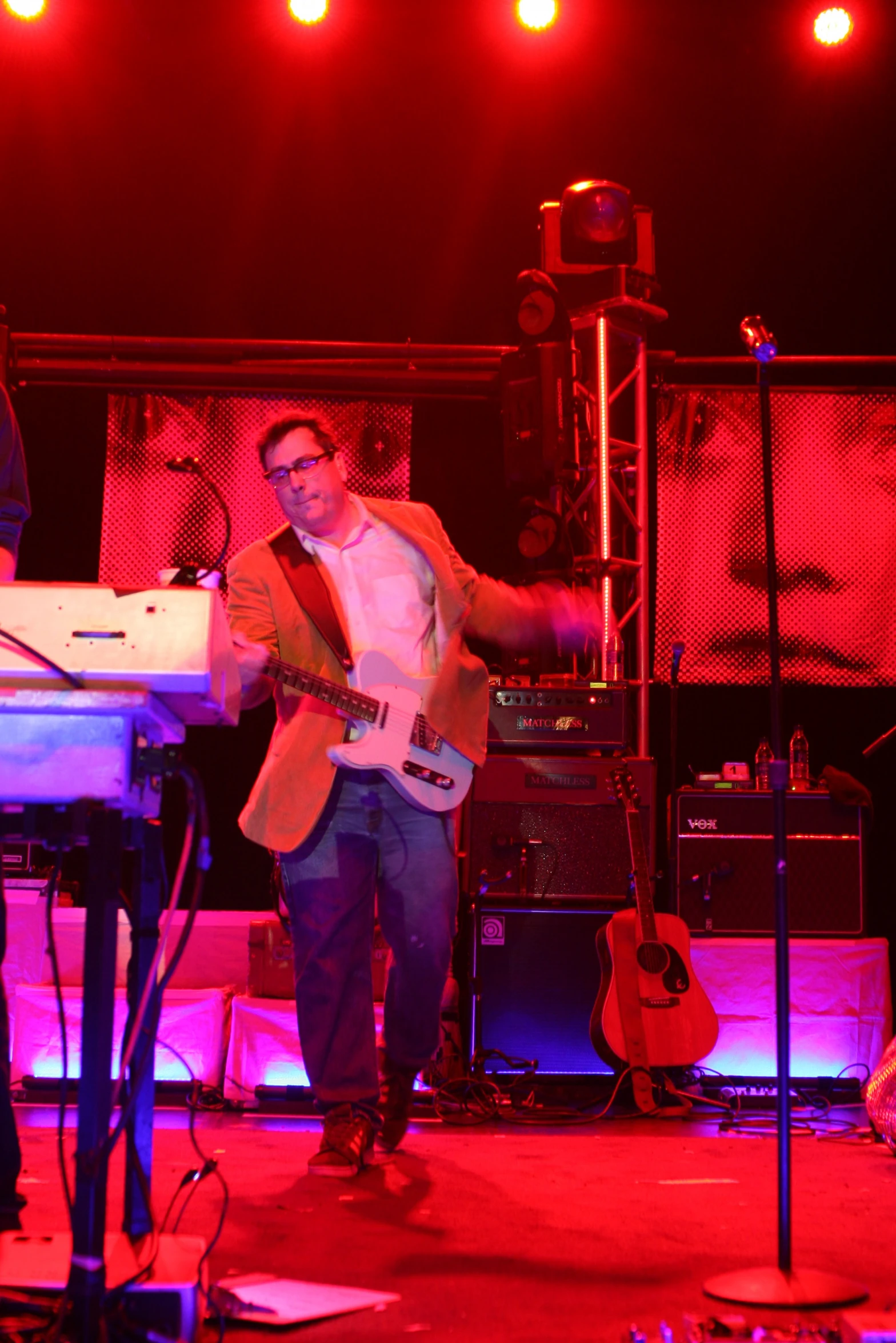 a man playing guitar on stage with other band mates