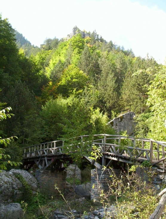 an old wooden bridge crosses over some small rocks