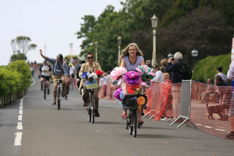 people are riding bikes down the street with many flowers on it