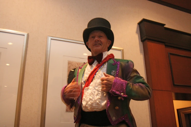 a man is dressed in colorful clothes standing near a wall