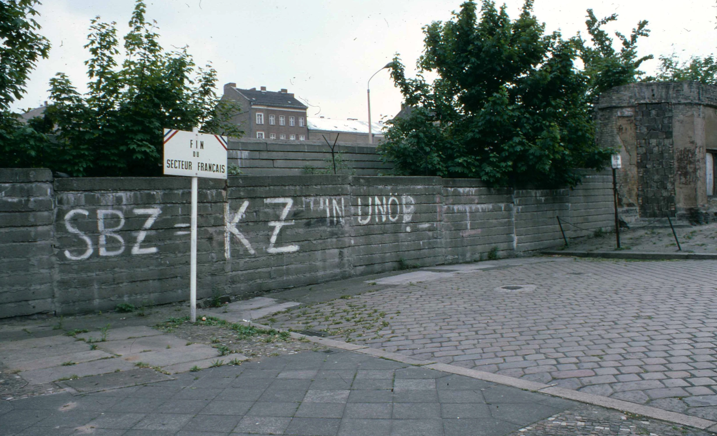 a wall and some brick sidewalk with trees on both sides