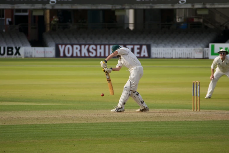 the man in white is playing cricket while another man watches