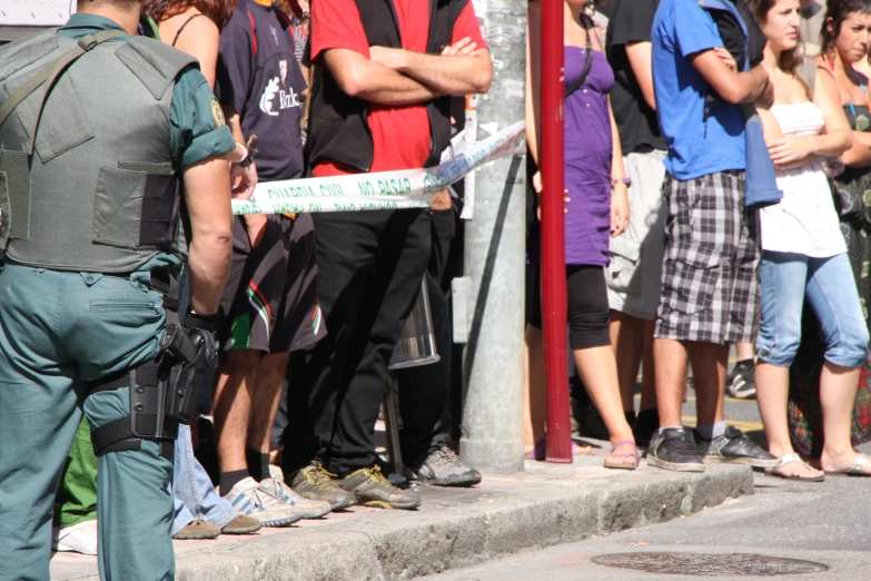 a group of people waiting on the side of a street to cross