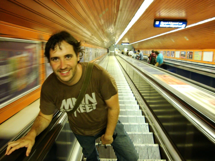 a smiling man riding an escalator down a train track