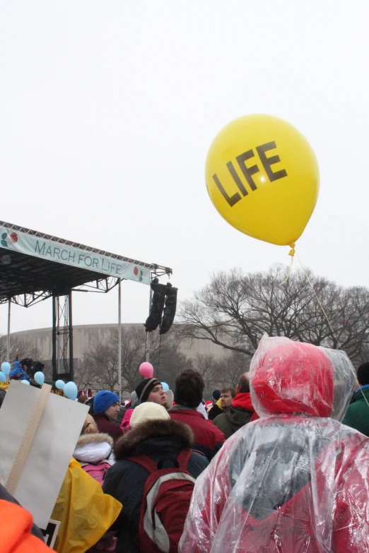 a crowd is watching an event with a large yellow life balloon