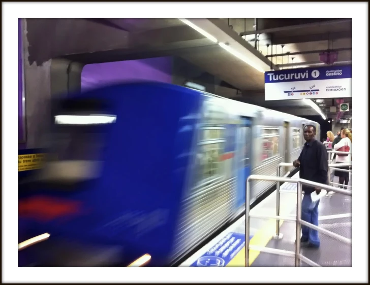 blurred pograph of train with people standing on platform