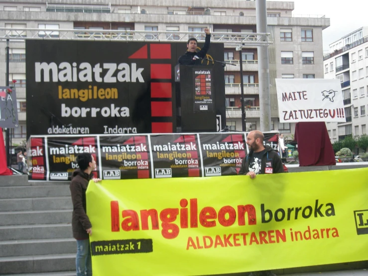 an outdoor event with people standing around and holding banners