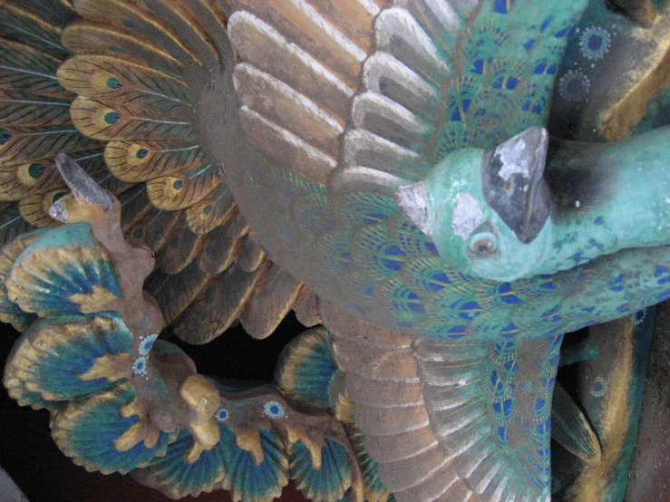 a metal sculpture of a peacock on a shelf