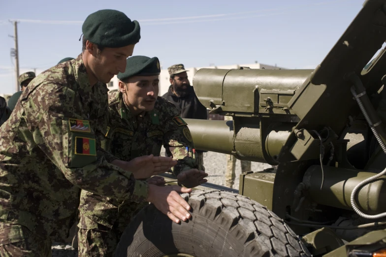 two soldiers examine soing on a tire