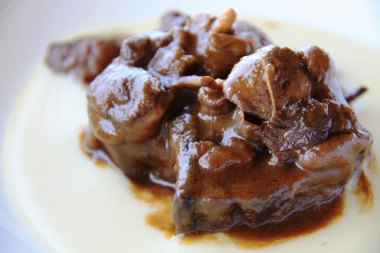 meat covered in brown sauce is on top of a plate