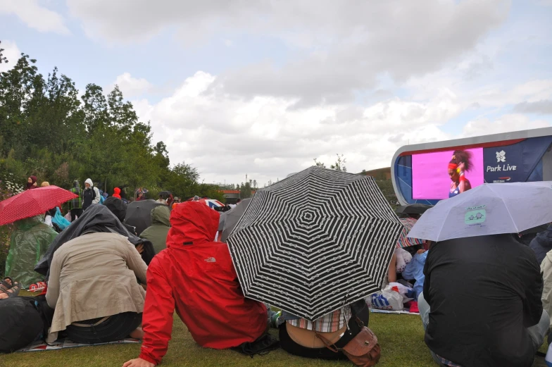 people sitting under umbrellas at an outdoor concert