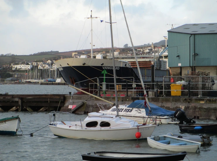 several boats sit in a dock as a tug boat is pulling up