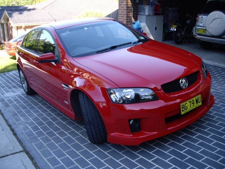 the front of a red car parked on the side of a road