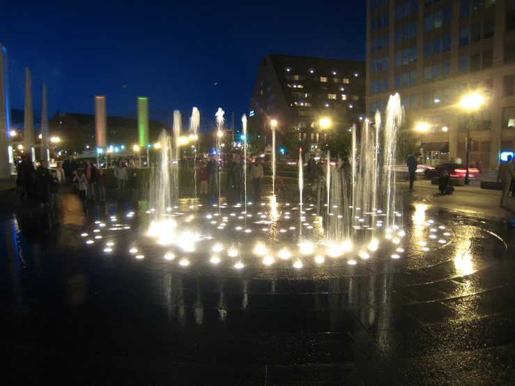 the city fountains are lit up on a late evening