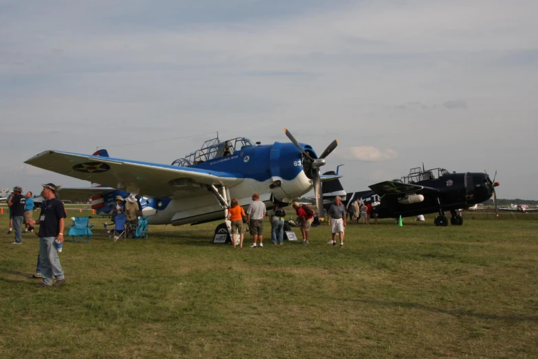 a group of people standing around a blue and white airplane