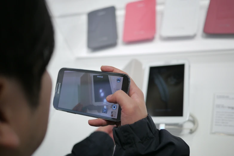 man holding up cell phone in front of various colored pographs