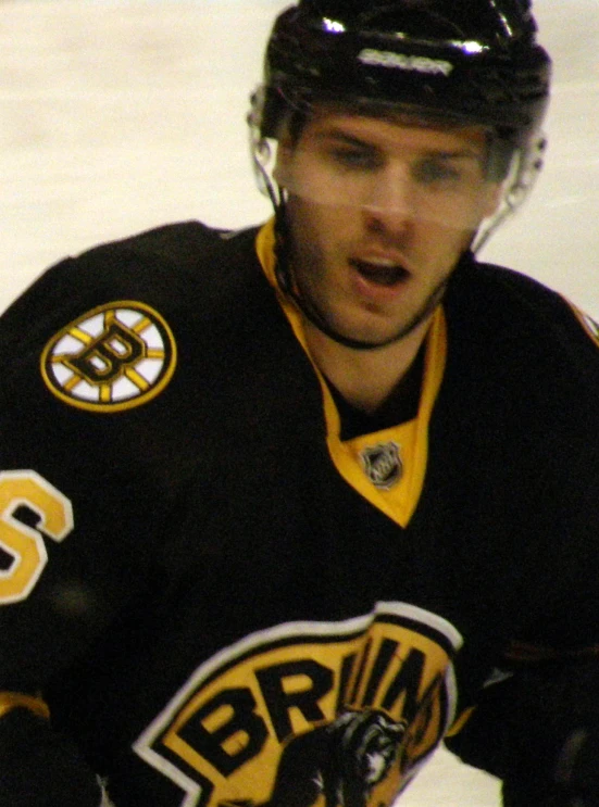 a man skating in an ice rink wearing a black and yellow hockey uniform