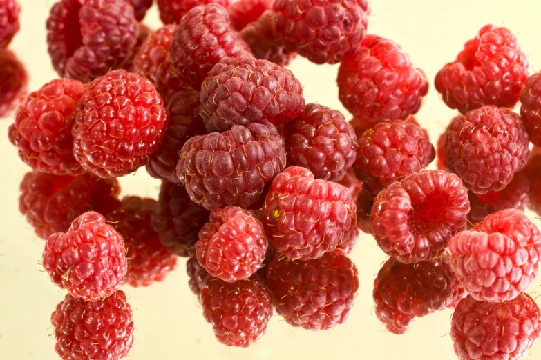 bunch of ripe raspberries on a white surface