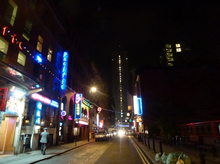 neon lights hang above the city street as pedestrians pass by