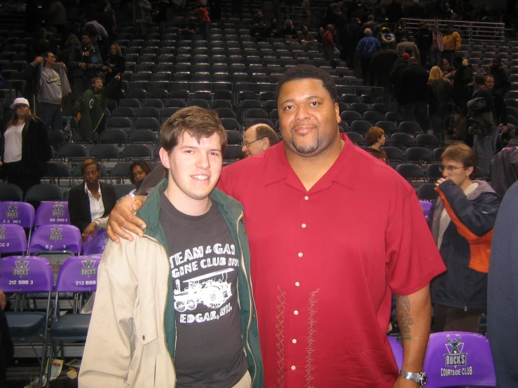 two men smiling at a stadium with a crowd