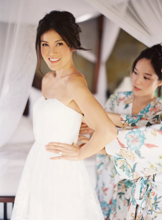 two asian brides helping to adjust the dress