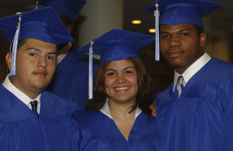 five graduating students posing in blue caps and gowns