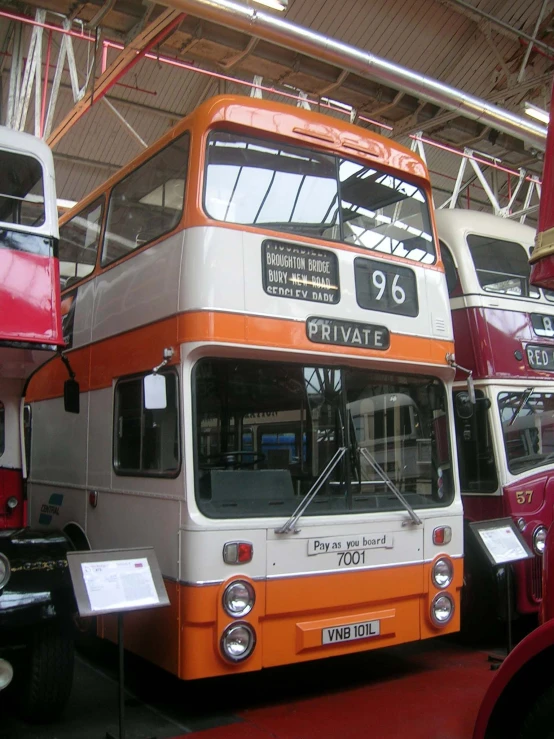 an orange and white double decked bus in a building