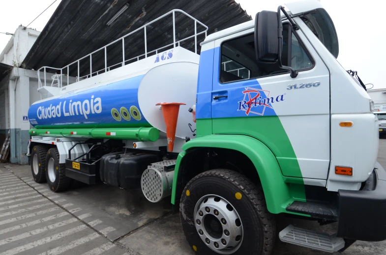 a fuel truck with a blue green white and red tank on it's flatbed