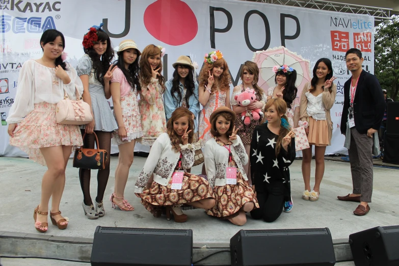 a group of s sitting and standing in front of a large poster