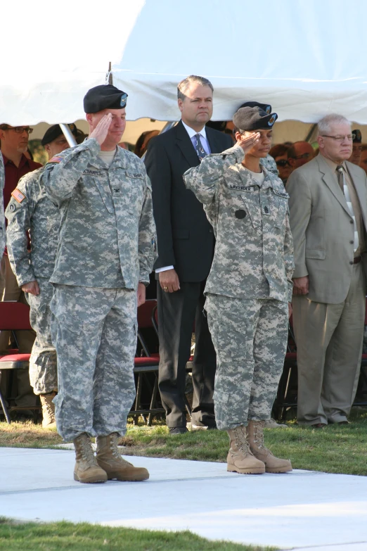 four military men stand in uniform during an outdoor ceremony