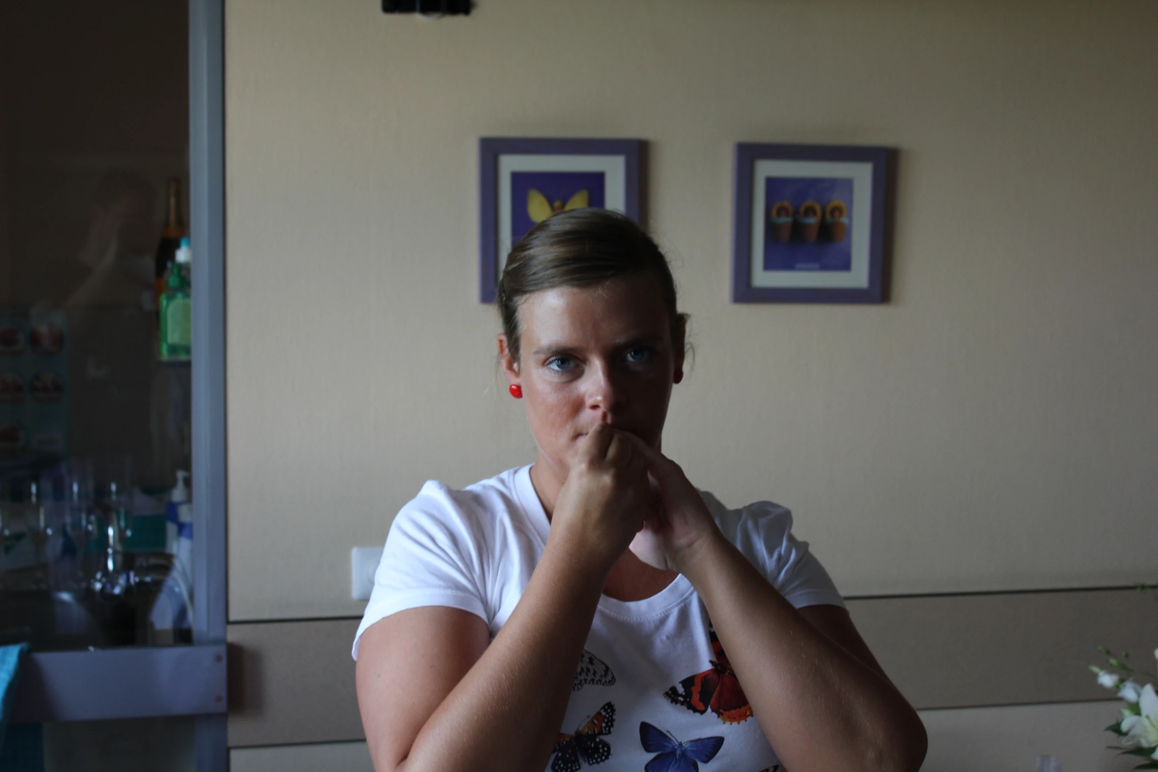 woman in white shirt sitting next to glass filled with water