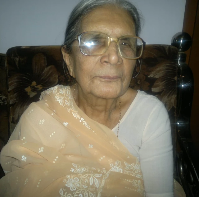 an older woman sitting in a chair with a lace covered headband