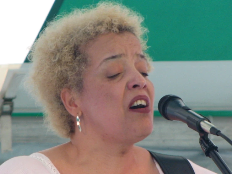 a woman singing on stage with her eyes closed