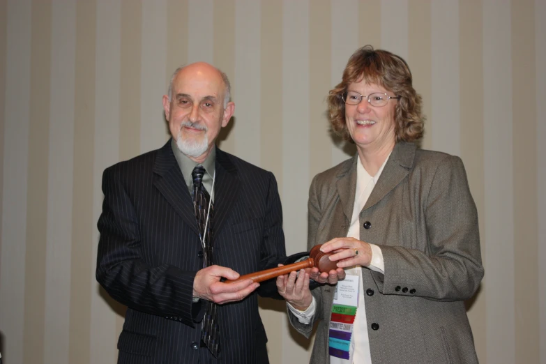 an old man and woman standing holding up a tie