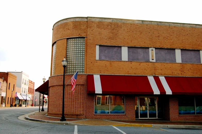 red brick building with awning in intersection with flags on pole