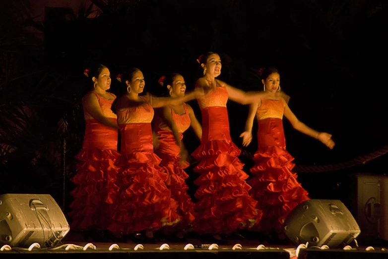 a group of women in orange dresses standing on a stage