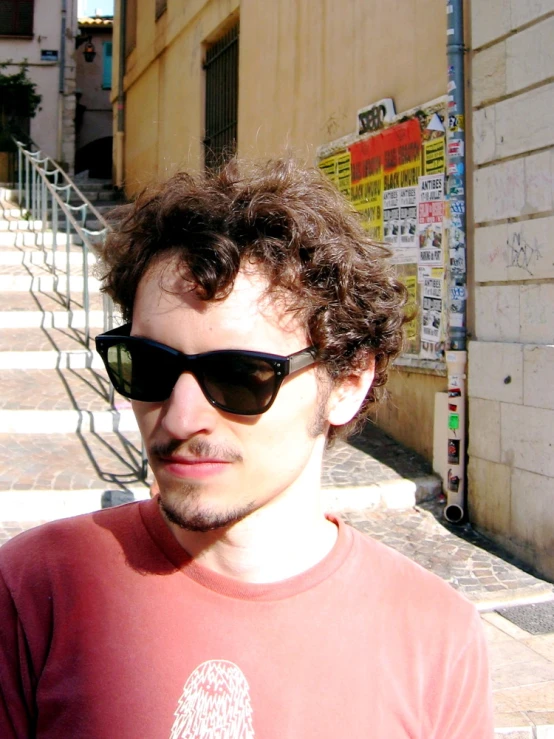 a man with large sunglasses standing on the sidewalk