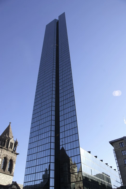 a tall glass skyscr reflecting another tall tower